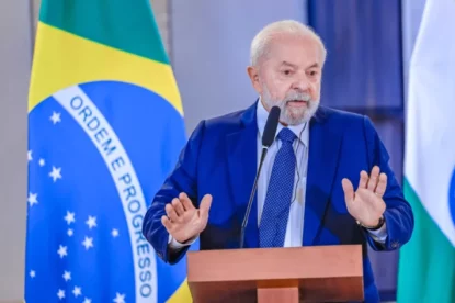 Presidente Lula em discurso em púlpito com bandeira do Brasil atrás.