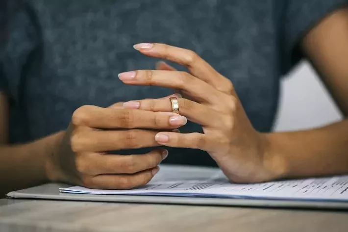 Mulher puxando uma aliança de casamento do dedo. Divórcio e fim do conceito de relacionamento