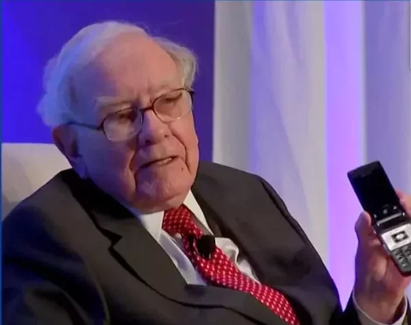 Foto mostra o bilionário Warren Buffett sentado com os lábios entreabertos.