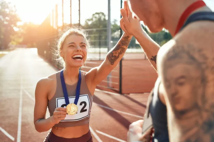 Imagem mostra atleta comemorando com uma medalha de ouro nas mãos