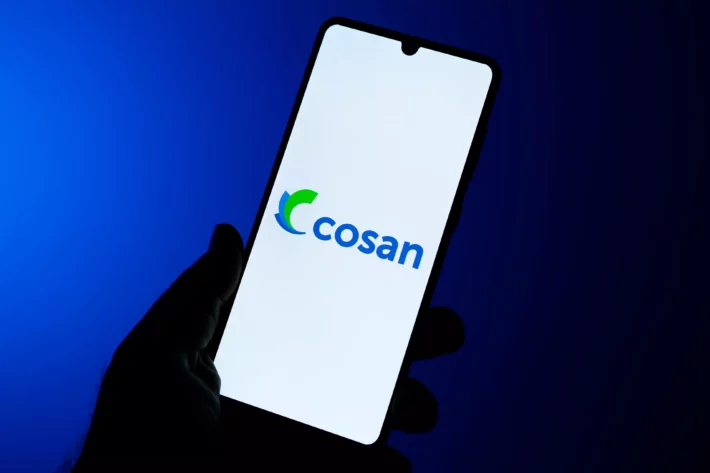 Foto mostra um celular cuja tela possui o logo da Cosan