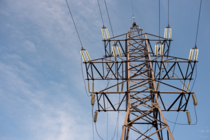 Setor elétrico empresas dividendos. Imagem mostra torre de transmissão de energia sob céu azul.