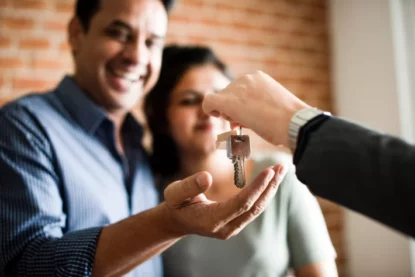 Casal alegre recebe nas mãos as chaves da sua nova casa. Financiamento imobiliário, casa própria.