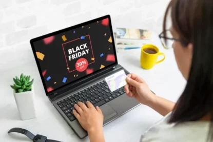 Imagem mostra mulher comprando online, pelo notebook, promoção da Black Friday.