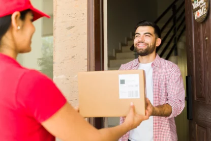 Jovem recebe feliz pacote de uma entregadora à sua porta.