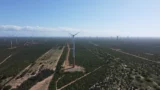 Imagem aérea de usina eólica. Aeris Energy (AERI3) reporta queda de 49,8% na receita operacional líquida no primeiro trimestre de 2026, refletindo a ausência de novos contratos e o ambiente doméstico cauteloso. (Imagem: Adobe Stock)