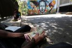 Morador venezuelano conta bolívares em frente a um mural do ex-presidente Hugo Chávez, em Caracas (Foto: Ivan Alvarado/Reuters)