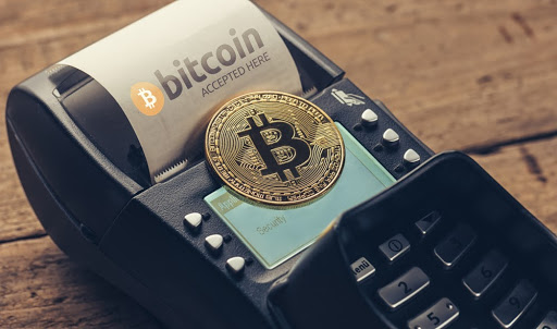 Moeda de bitcoin aparece em cima de máquina de cartão de crédito