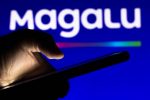 Celular manuseia celular em frente ao logo da Magalu