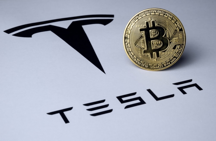 Moeda de bitcoin ao lado da logo da Tesla