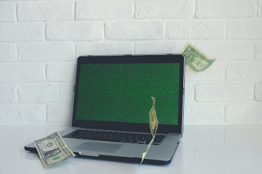 Laptop com tela verde próximo a cédulas de dólar