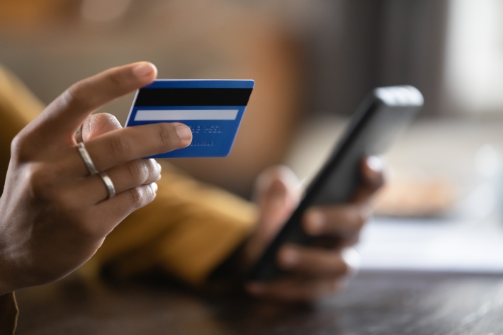 A imagem mostra uma mulher segurando um cartão de crédito com o intuito de usá-lo para fazer um Pix.