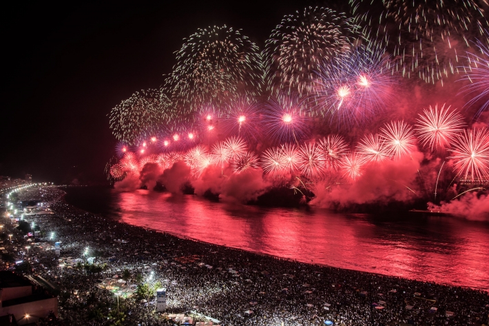 the picture shows fireworks on ships in the sea by the beach, reminiscent of New Year's fireworks.